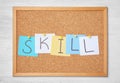 Notes with word SKILL pinned to cork board