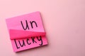 Notes with word UNLUCKY on pink background. Space for text