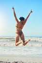 Nothing beats a sunny day on the beach. Rearview shot of a young woman standing on the beach.