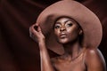 Nothing gives confidence like glowing skin. a beautiful young woman wearing a hat while posing against a brown