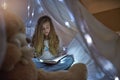 Nothing like a good book before bedtime. a young girl reading a book under a blanket fort at home. Royalty Free Stock Photo