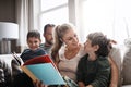 Nothing says family time like story time. two adorable brothers reading a book together with their parents while Royalty Free Stock Photo