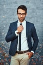 Nothings out of place. Cropped portrait of a handsome young businessman adjusting his tie while standing against a grey Royalty Free Stock Photo