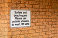Notice on a brick wall - Surfers and beach-goers please use outside showers to wash off sand
