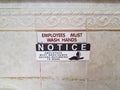 Notice employess must wash hands sign on bathroom wall Royalty Free Stock Photo