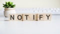 Notify word made with wooden blocks on background white keyboard