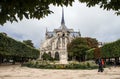 The Notre Dame de Paris church in a rainy day against the overcast sky and two people walking near the church and sharing one umbr