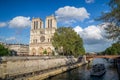 Notre Dame de Paris in a sunny day, view from the rive Seine with tourists and cruise