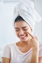 Nourished skin glows beautifully. a beautiful young woman applying moisturizer to her skin in the bathroom at home.