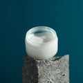 Nourishing face or body cream on a granite cube, blue background Royalty Free Stock Photo