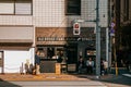 Japanese business man walking on Tokyo street under high contrast afternoon light with modern burger shop