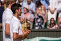Novac Djokovic, Wimbledon winner, holds the trophy on centre court with Kevin Anderson standing to his side, partly obscured.