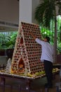 Man building large gingerbread house in a commercial setup