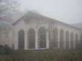 November afternoon in white thick fog, walk in the castle forest park in dry weather, old building in the gray afternoon Royalty Free Stock Photo