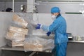 Meat factory. An enterprise worker in a protective suit and a medical mask is packing boxes