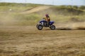 Man in red helmet riding a blue quad on autumn track