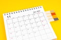 The November 2023 Monthly desk calendar and blank adhesive note on yellow background Royalty Free Stock Photo