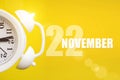 November 22nd. Day 22 of month, Calendar date. White alarm clock on yellow background with calendar day. Autumn month, day of the