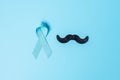 November Prostate Cancer Awareness month, light Blue Ribbon with mustache on wooden background for supporting people living and