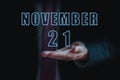 november 21st. Day 20 of month, announcement of date of business meeting or event. businessman holds the name of the month and day