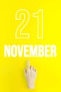 November 21st . Day 21 of month, Calendar date.Hand finger pointing at a calendar date on yellow background.Autumn month, day of