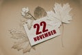 november 22. 22th day of month, calendar date.Envelope with the date and month, surrounded by autumn leaves on brown