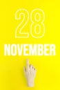 November 28th. Day 28 of month, Calendar date.Hand finger pointing at a calendar date on yellow background.Autumn month, day of