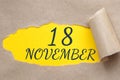 november 18. 18th day of the month, calendar date.Hole in paper with edges torn off. Yellow background is visible