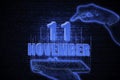 November 11th. A hand holding a phone with a calendar date on a futuristic neon blue background. Day 11 of month.