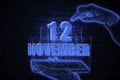 November 12th. A hand holding a phone with a calendar date on a futuristic neon blue background. Day 12 of month.