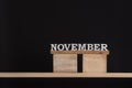 November by wooden letters. Black background. Front view. Autumn calendar. Copy space