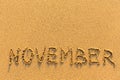 November - word inscription on the gold sand beach.