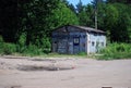 An old closed garage with the inscription `tire service` stands on a vacant lot near the road.