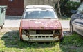 Old damaged and rusted Yugoslavian Zastava Yugo car with broken windscreen or windshield and peeled paint on the hood.