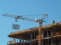 A worker standing on the building construction controls the lifting of the load crane Royalty Free Stock Photo