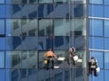 Three workers cleaning the glass building`s windows