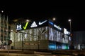 06.01.2023, Novi Sad, Serbia. Night city and facade of shopping mall with glowing logos of brands Adidas, Lcwaikiki