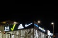 06.01.2023, Novi Sad, Serbia. Night city and roof facade of shopping mall with glowing logos of brands Adidas, Lcwaikiki