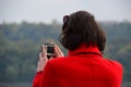 Woman in red coat taking picture with action camera