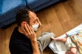 Novice father changing the smelly diaper of a baby, wearing a mask for bad smells with a gesture of disgust Royalty Free Stock Photo