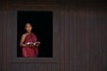 Novice monk smiles at the old temple window