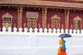 Novice monk walking past ancient temple of Vatsensoukharam, ancient buddhist temple with beautiful mural painting.