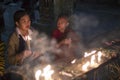 Novice monk and woman lighting candles at a Buddhist temple Royalty Free Stock Photo