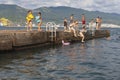 Novorossiysk, Russia - August 5, 2022: Children and adults are jumping from the pier of the city beach of Novorossiysk