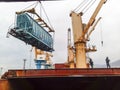 Moving freight railway car in the port by a port crane. Cargo lifting operations. Industrial port.