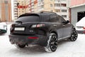 Black expensive tuned car Infiniti Fx 35 in the old body stands with the engine turned on in the winter against the background of Royalty Free Stock Photo