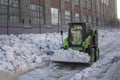 Green snowblower removes snow from the city streets