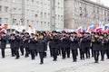 A military arcade with a large number of musicians in black full dress with brass instruments and Russian flags during a parade