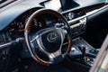 Modern steering wheel with wood elements and metallic chrome parts in the design of an expensive Lexus car on the background of