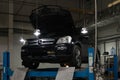 Used black car Mercedes Benz GL with an open hood raised on a four-post lift for repairing the chassis and engine in a vehicle